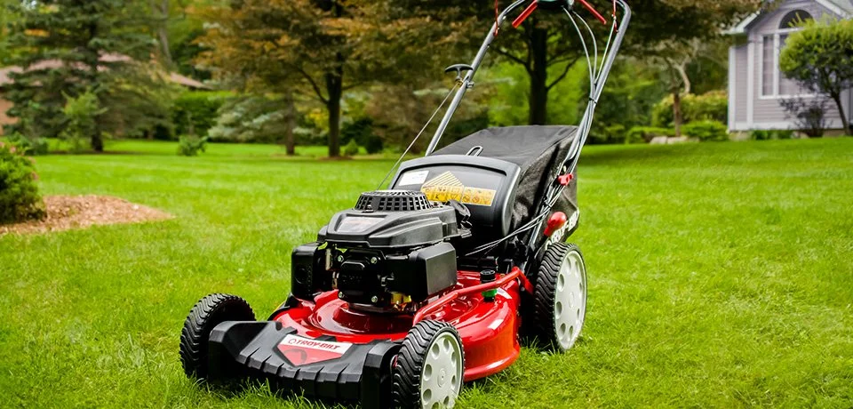 A walk-behind lawn mower on a green residential lawn
